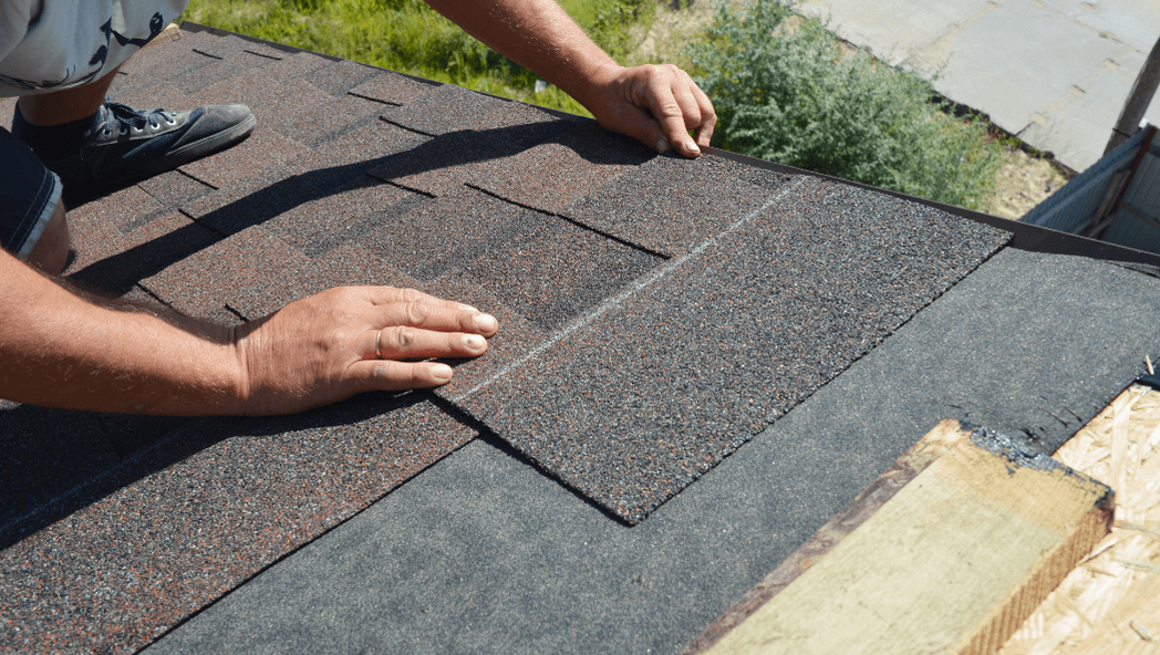 Roofer installing medium gray shingles on a roof